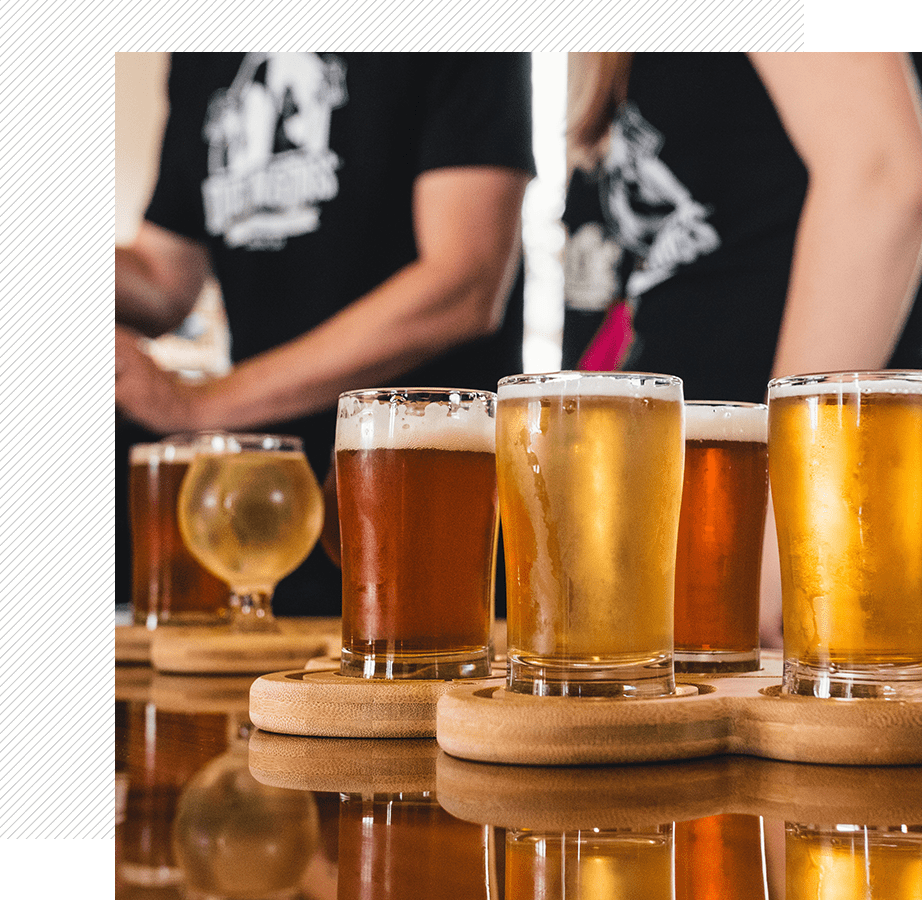 A group of people standing around some beer glasses.